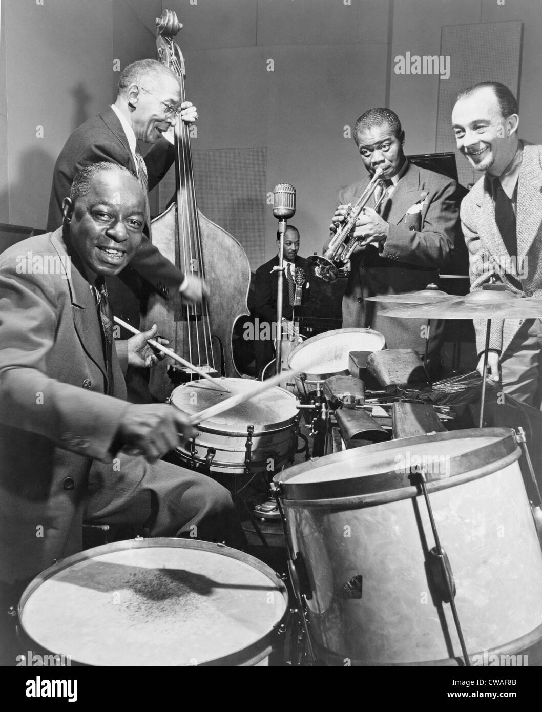 Louis Armstrong (1901-1971), playing trumpet with others during a 1947 broadcast of "This is Jazz" radio show, directed by Rudi Stock Photo