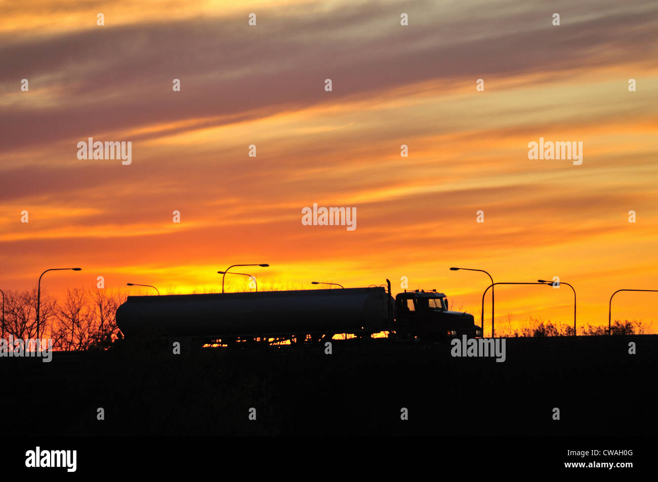 Schaumburg, Illinois, USA. A semi-tractor tanker trailer makes its way along a stretch of highway in suburban Chicago in front of a colorful sunset. Stock Photo