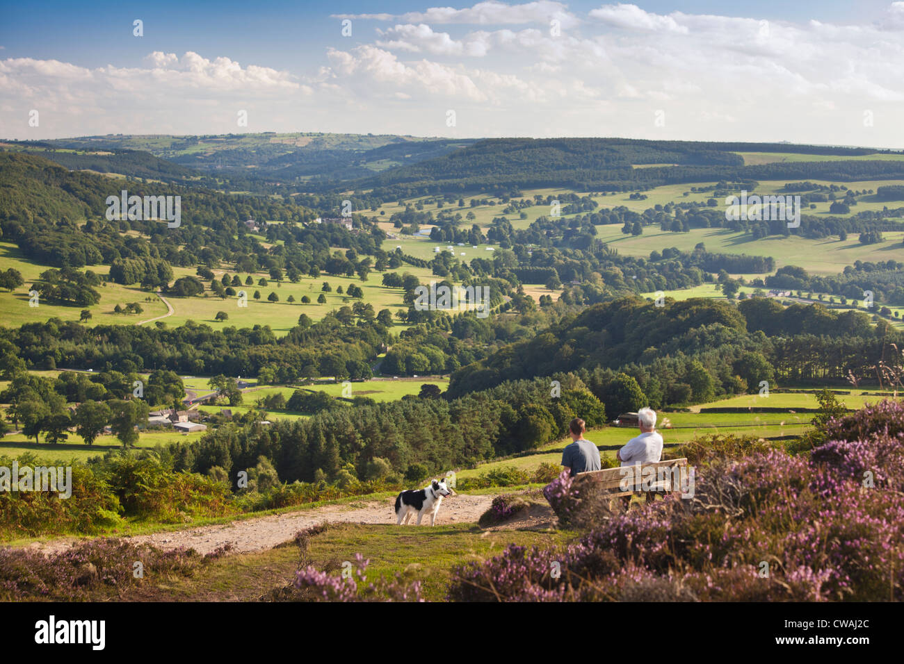 Walkers admire the view from Baslow Edge over the Derwent Valley and Chatsworth Park, Derbyshire, England, UK Stock Photo