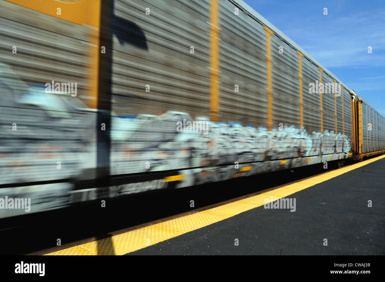 Train of auto rack carriers blur of motion through Geneva, Illinois on its way westbound from Chicago. Geneva, Illinois, USA. Stock Photo