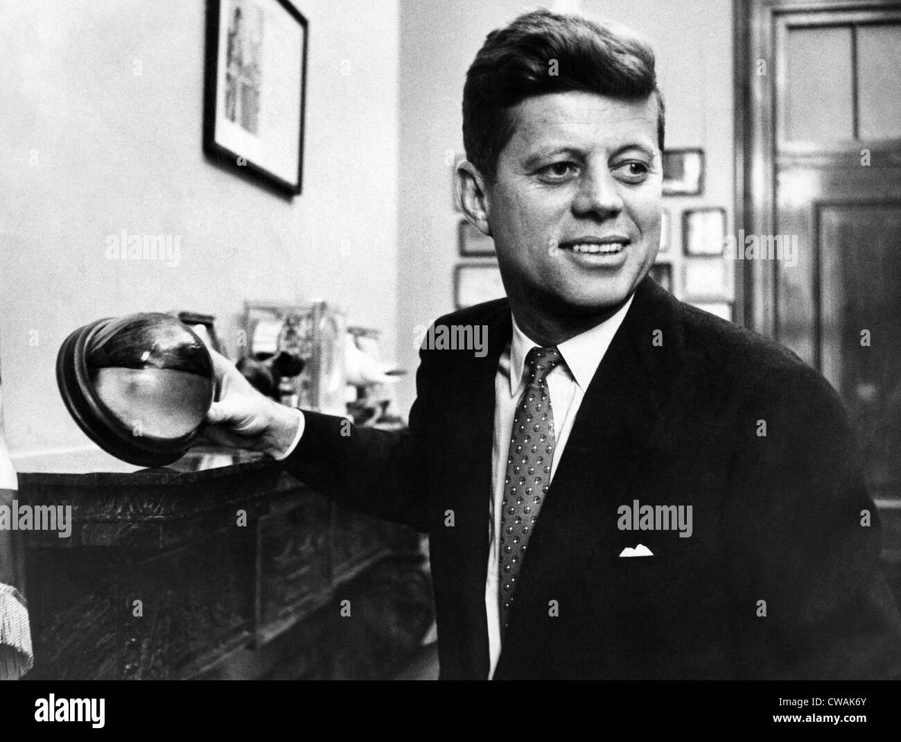 Senator John F. Kennedy, holds a mounted half of a cocoanut in his Senate office. After his boat was torpedoed during World War Stock Photo