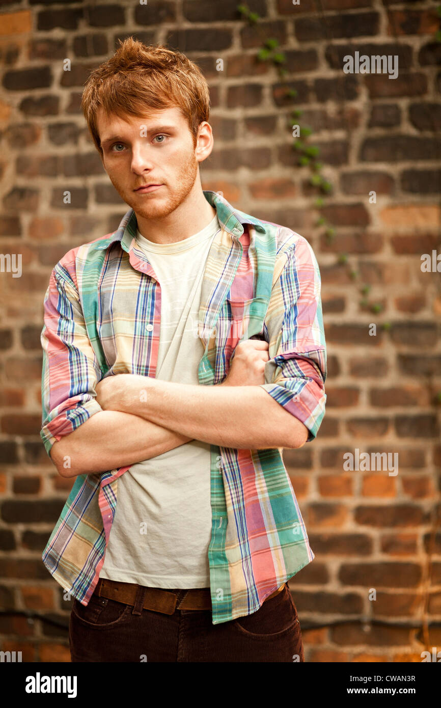 Portrait of young man in front of brick wall Stock Photo - Alamy