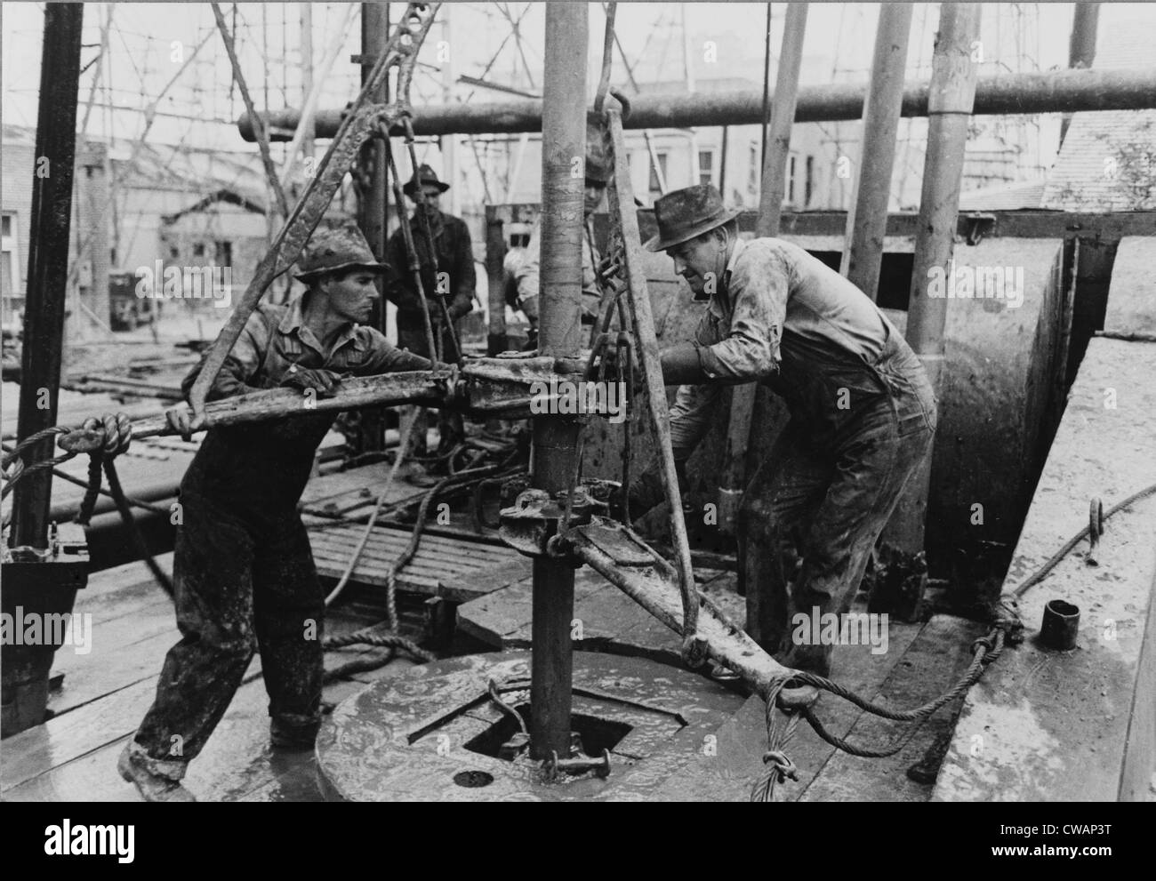 Oil roughnecks screw one piece of drill pipe to another piece with a