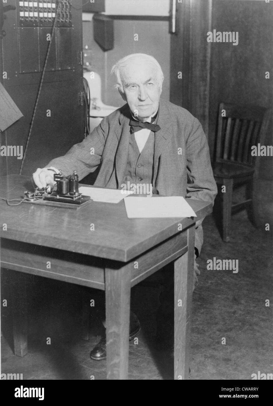 Thomas Edison, seated at desk, demonstrating an old telegraph transmitter in his West Orange, New Jersey, laboratory, 1930. Stock Photo