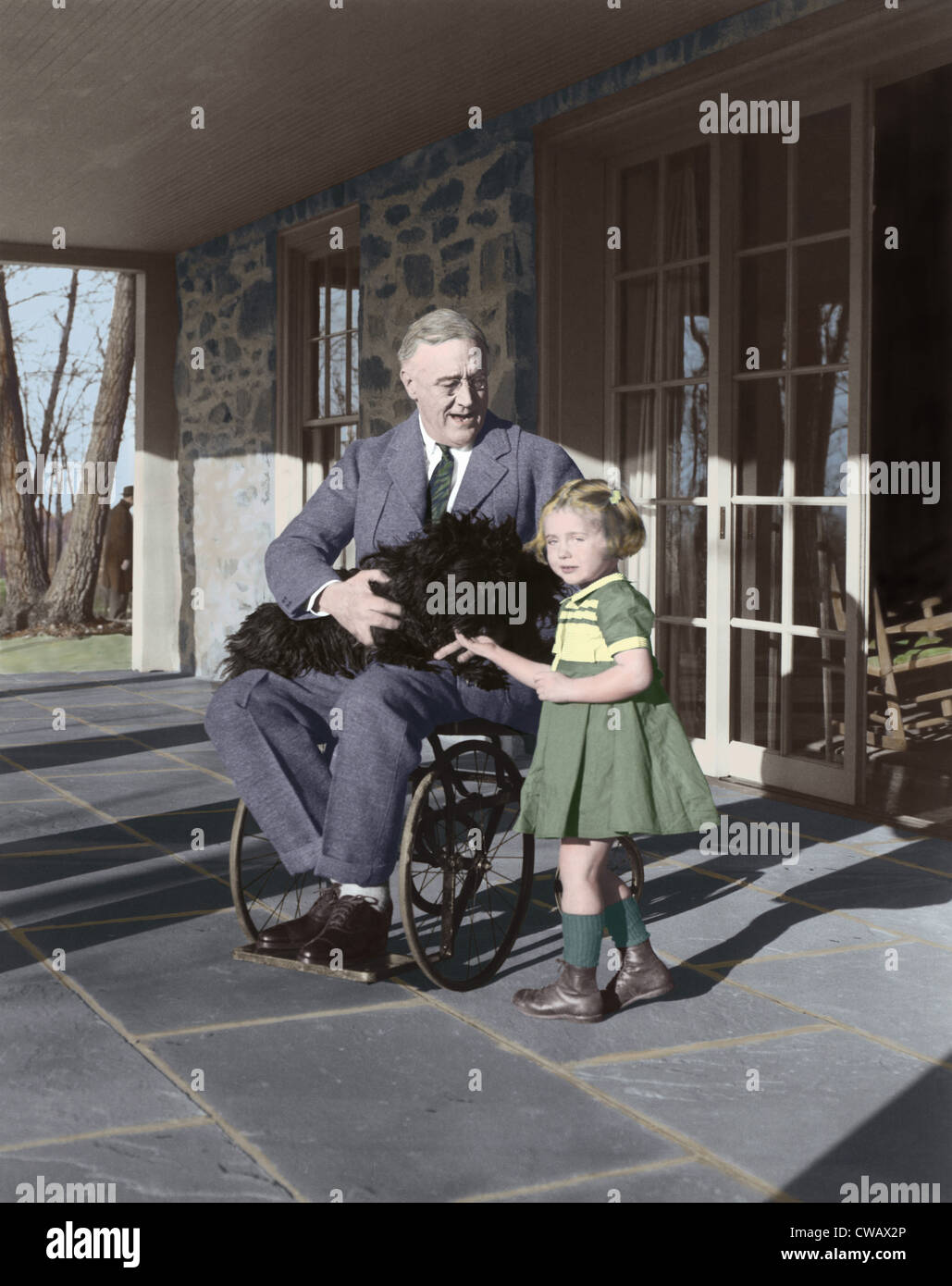 President Franklin Delano Roosevelt in his wheelchair on the porch at Top Cottage in Hyde Park, NY, with Ruthie Bie and Fala. Stock Photo