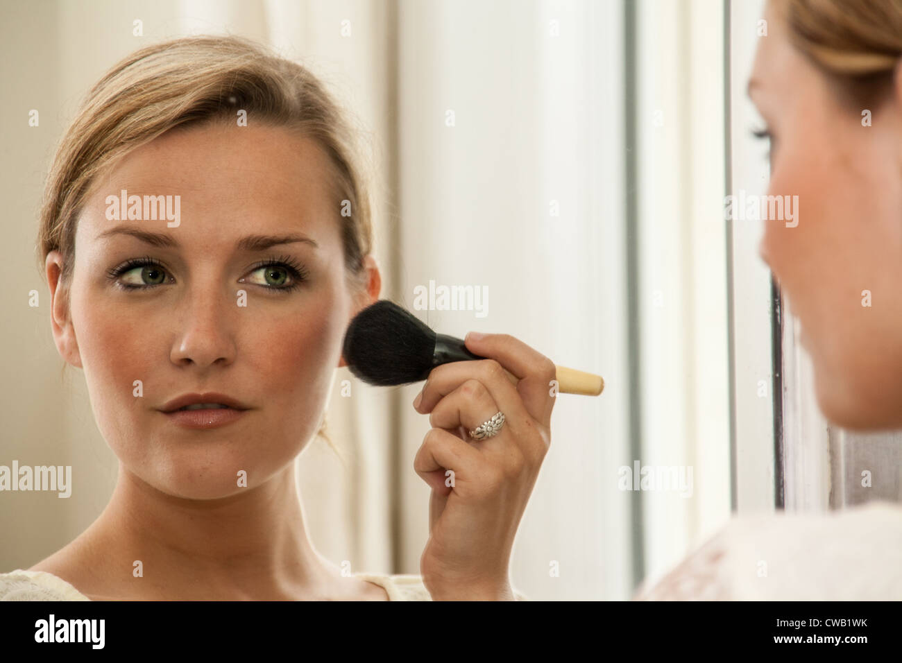 Woman applying blusher to her cheeks, reflected in a mirror Stock Photo