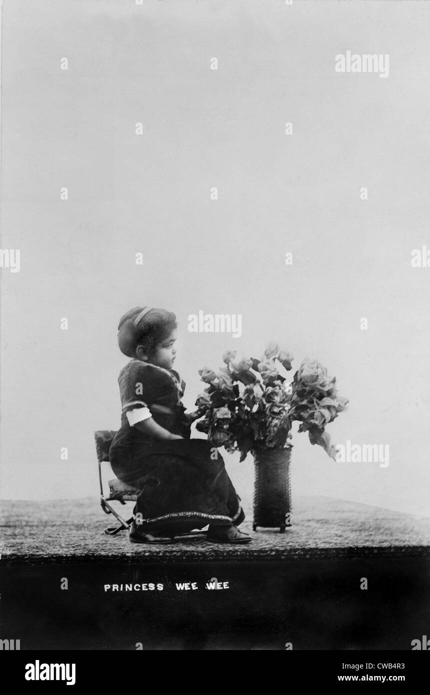 Princess Wee Wee, African American dwarf, full-length portrait, seated, facing right, with bouquet of flowers, 1915. Stock Photo