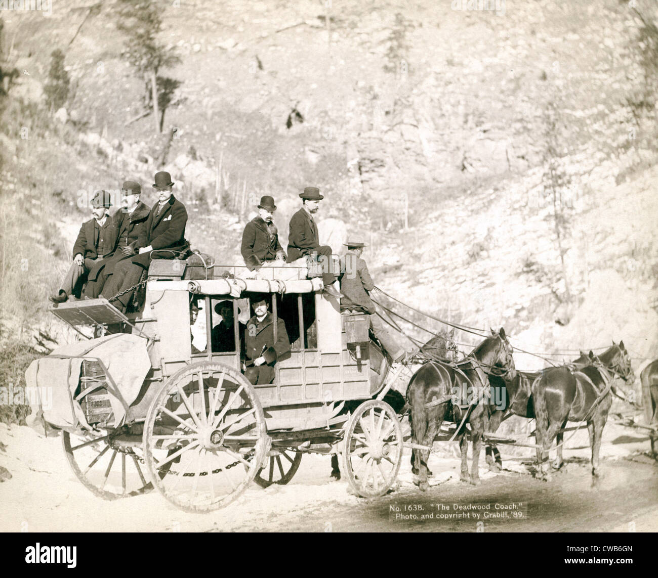 The Deadwood Coach. Side view of a stagecoach; formally dressed men sitting in and on top of coach. Deadwood, SD. John C. Stock Photo