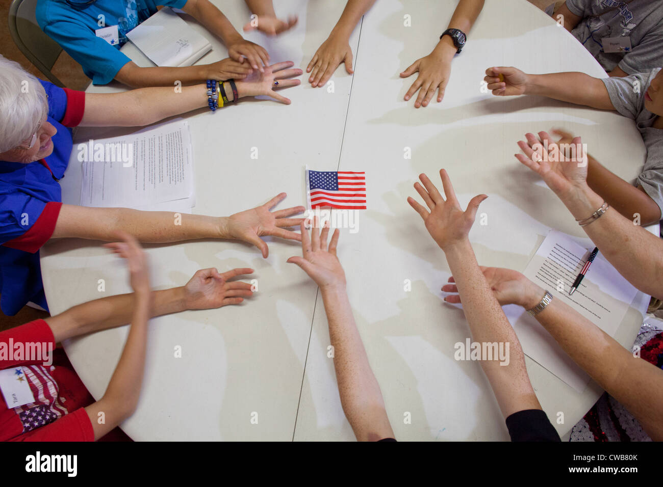 Students stretch hands toward center of table during lesson at 'Vacation Liberty School' session Stock Photo