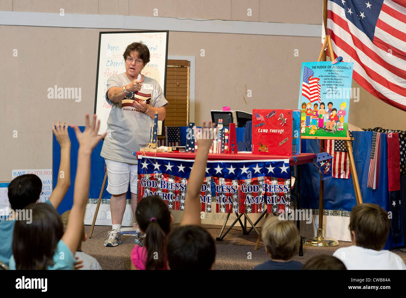 Students raise hands to answer adult volunteer's question during lesson at 'Vacation Liberty School' session near Austin, Texas Stock Photo