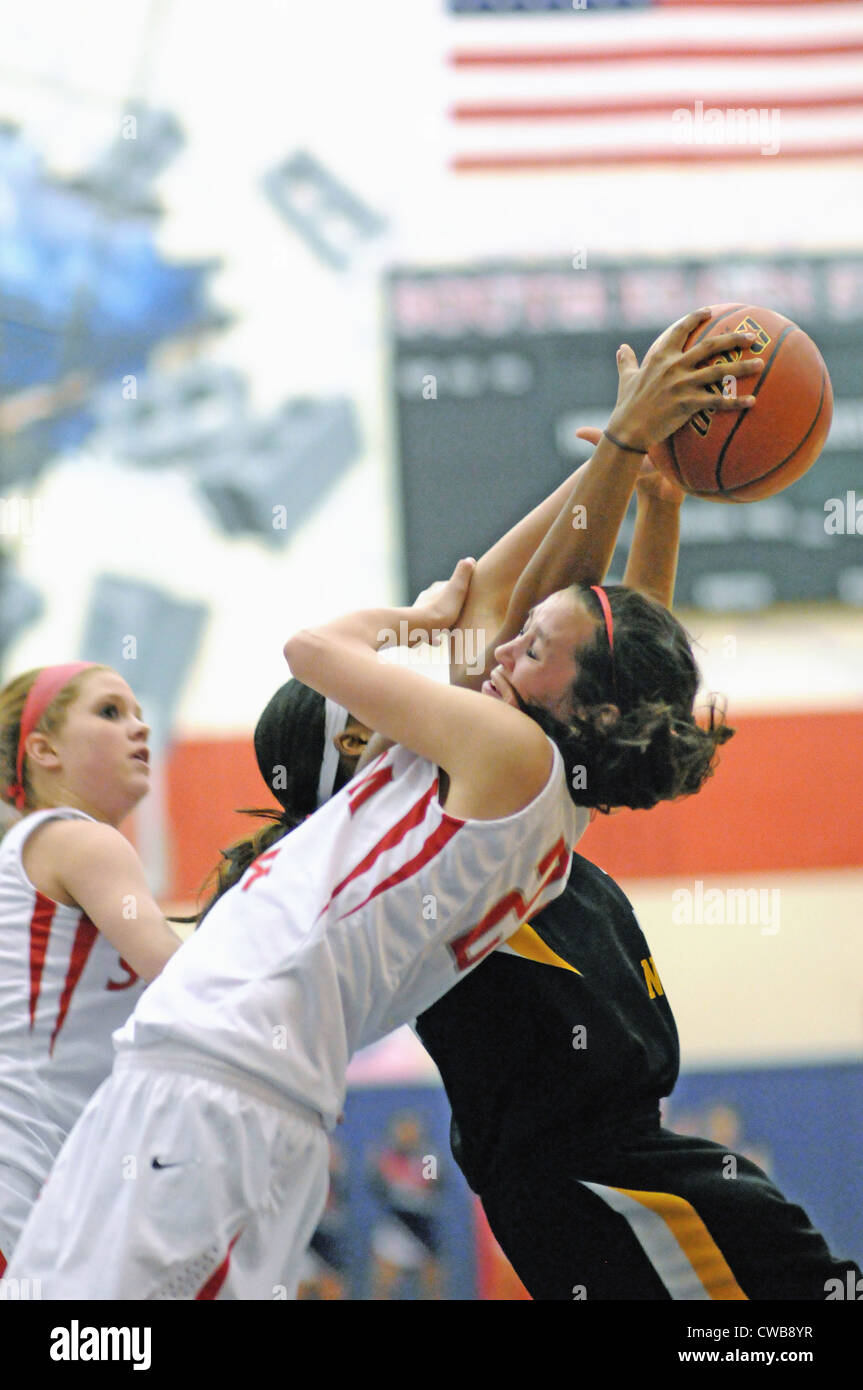 Basketball Player falls backward toward the hardwood as she battles for