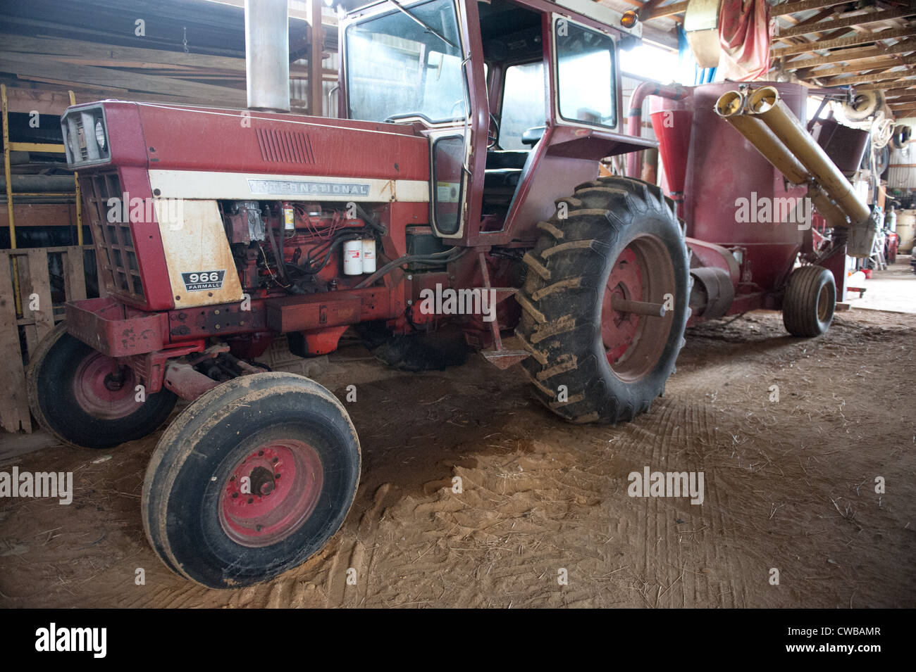 Antique tractor and machinery in barn on farm Stock Photo