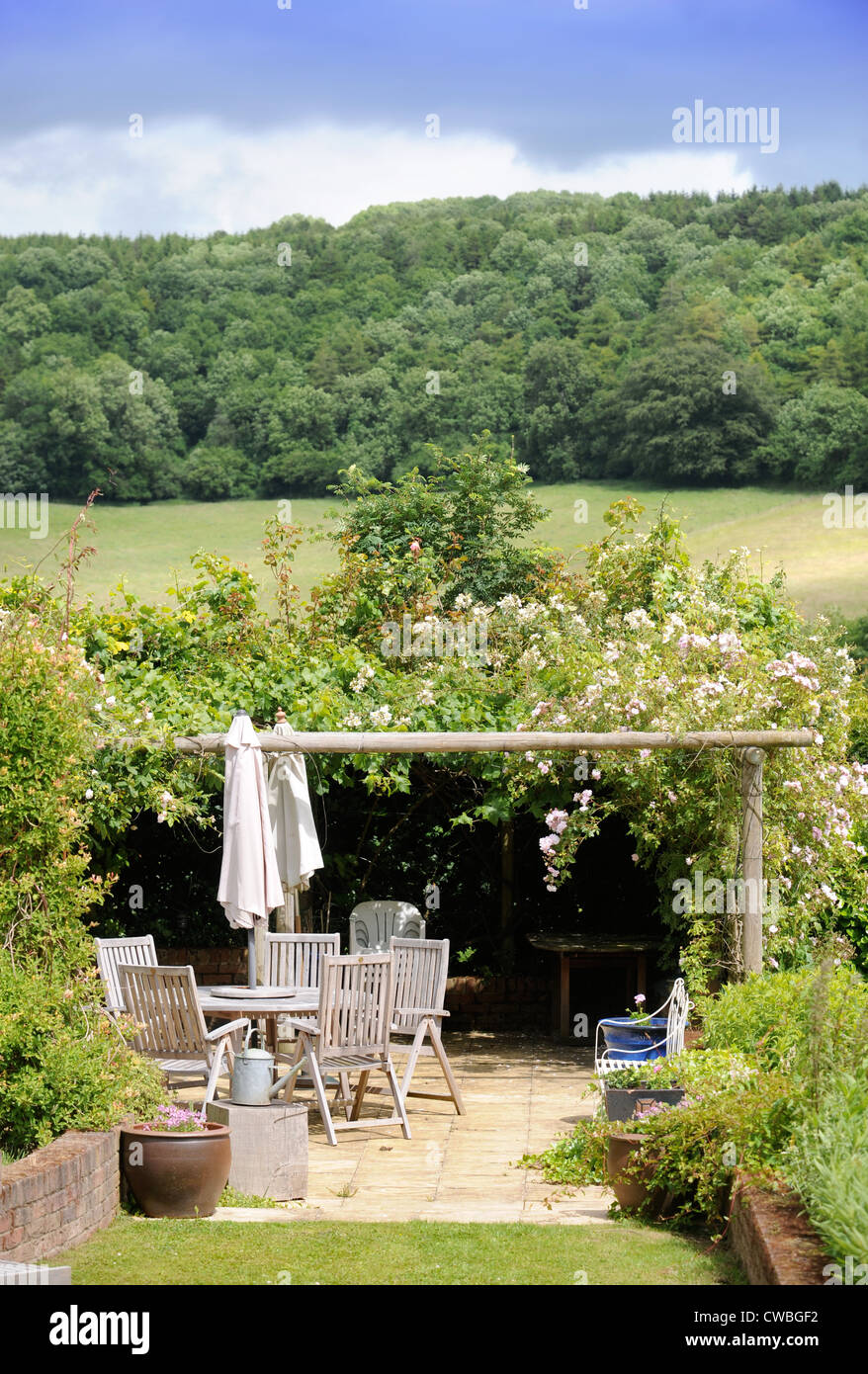 A garden patio table and chairs beneath an arbor in a countryside setting England UK Stock Photo