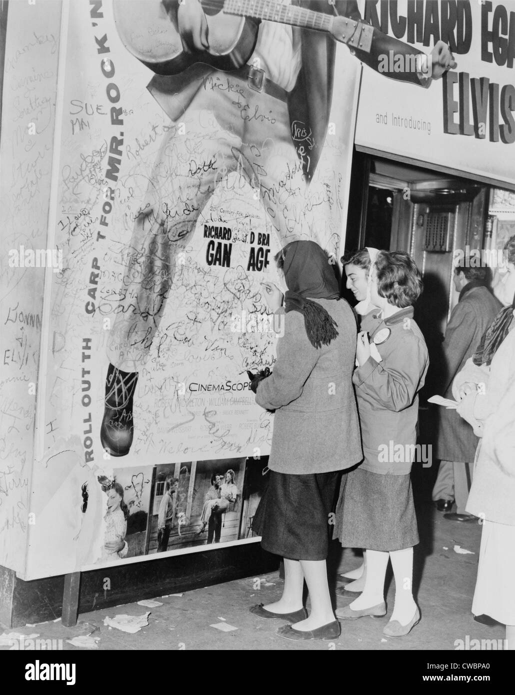 Teenage girls add graffitti to LOVE ME TENDER movie poster, Elvis Presley's film debut. 1956 Stock Photo