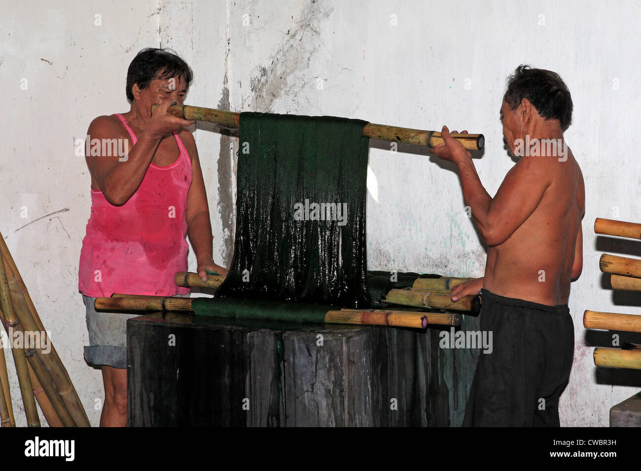 A process of Ikat fabric weaving. The warp thread is dyed a solid color. Stock Photo