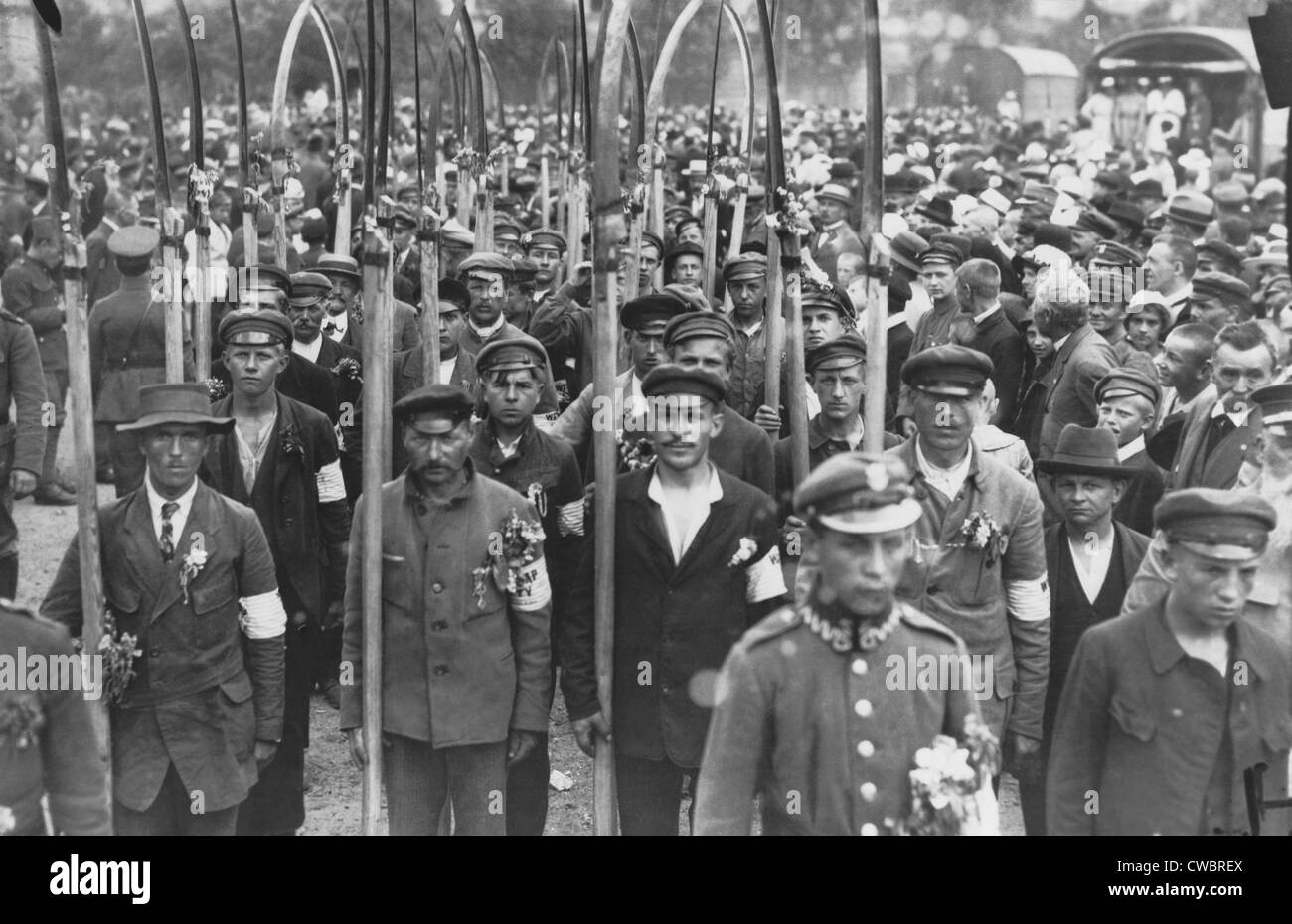 Polish army volunteers with scythes in a crowd of people in July 1920. The Russo-Polish War of 1919-20 followed the creation of Stock Photo