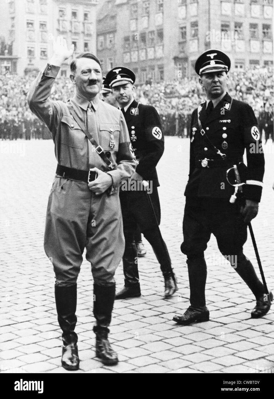 Adolf Hitler saluting, with two SS generals in uniform behind him, at