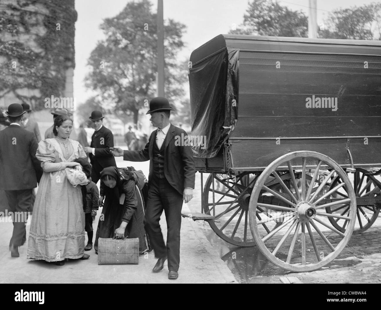 Two women immigrants and a child engage a wagon for transport to their next stop, probably a boarding house or railroad Stock Photo