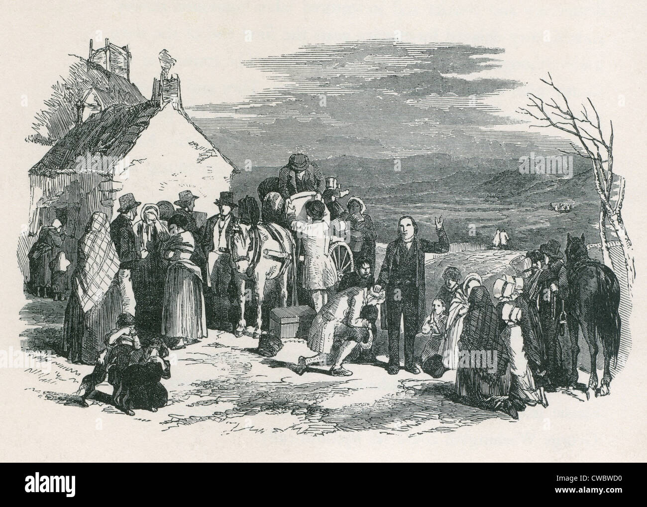 A Catholic priest blesses kneeling immigrants as they to leave their homes and families in Ireland for North America during the Stock Photo