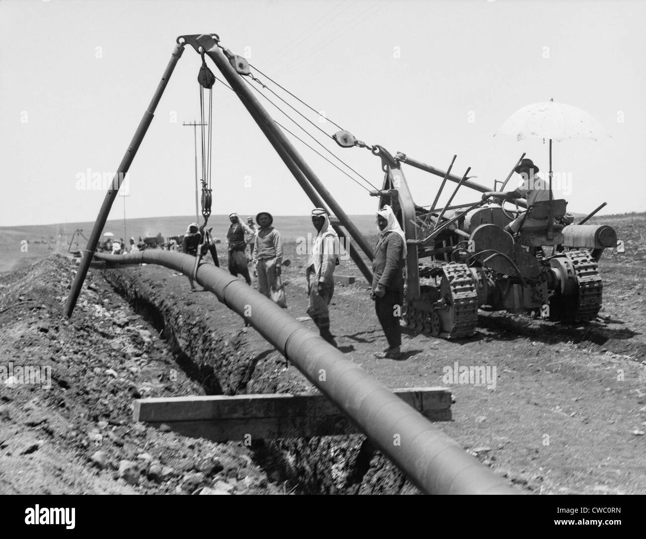 Dropping a welded pipe into a trench with a crane while laying the Iraq Petroleum Company's pipe line across Palestine's Plain Stock Photo