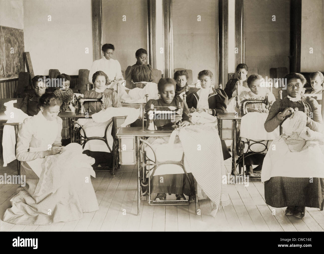 Young African American women sewing with machines and by hand in the sewing class at the