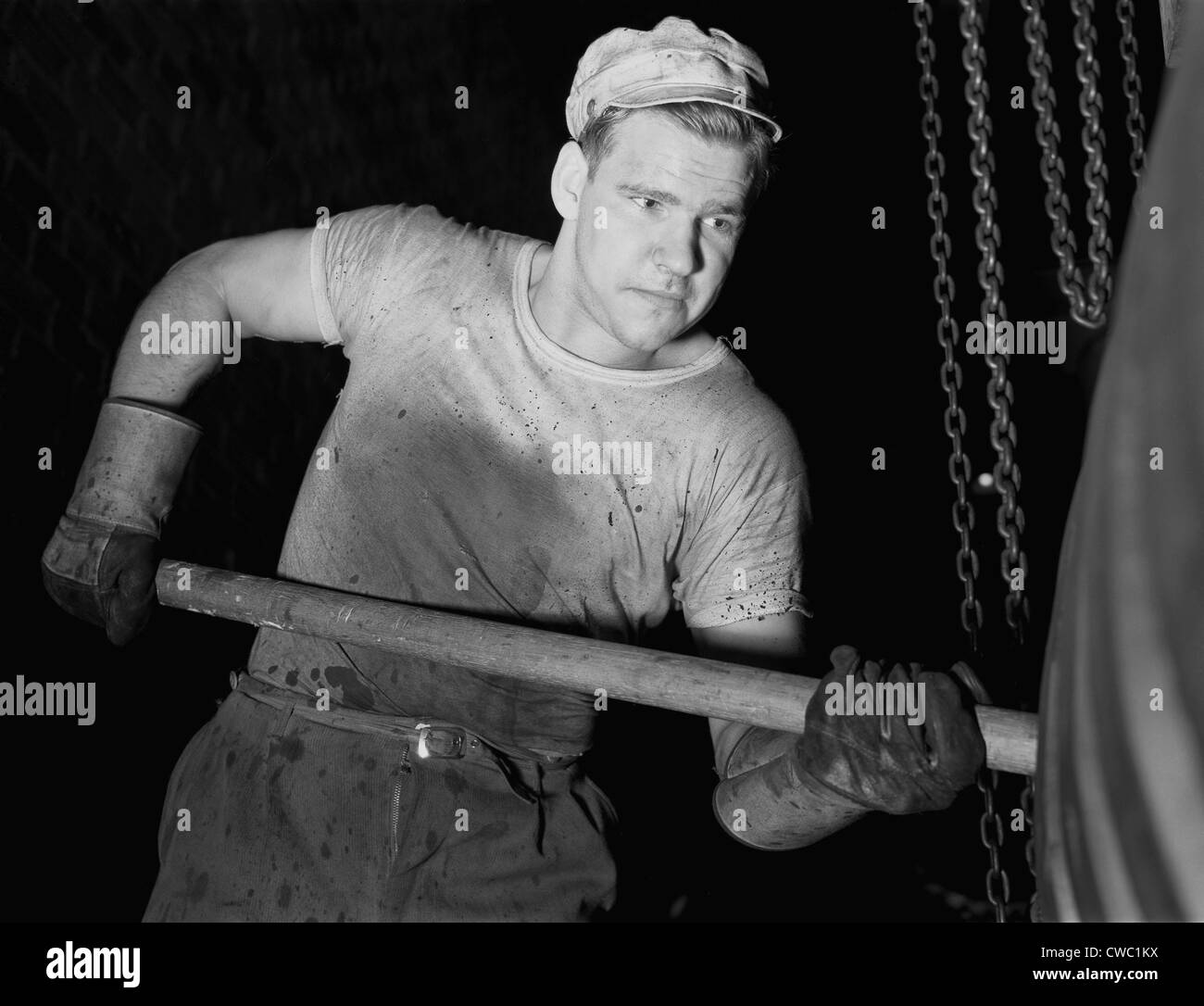 Defense worker at the Goodrich rubber plant molding rubber with a wooden paddle. December 1941. Stock Photo