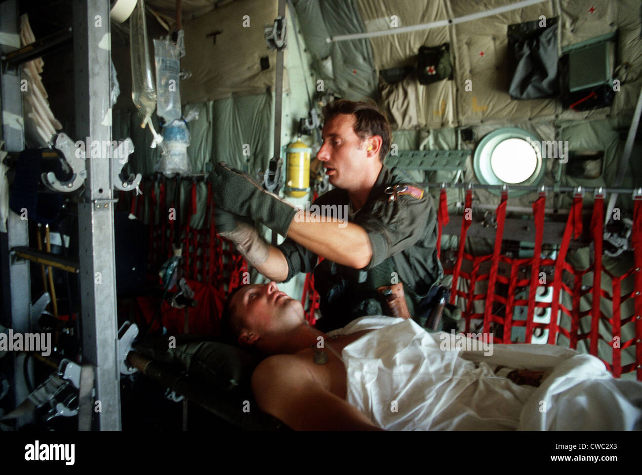 A medic adjusts the intravenous drip bag of a wounded US serviceman en route to a medical facility after the invasion of Stock Photo