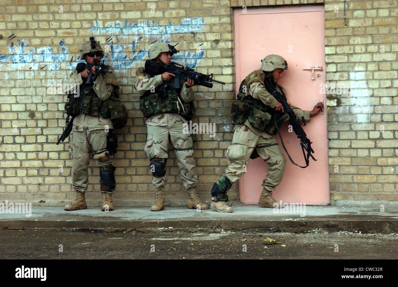 U.S. Army soldiers are poised to enter a building in Fallujah Iraq. Second Gulf War Nov. 9 2004. (BSLOC 2011 3 10) Stock Photo