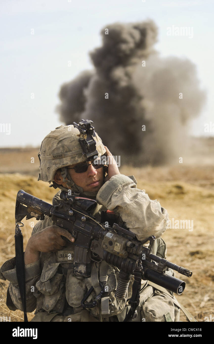 U.S. Army soldier with covers his ear as a controlled detonation destroys an improvised explosive device in Badula Qulp Stock Photo