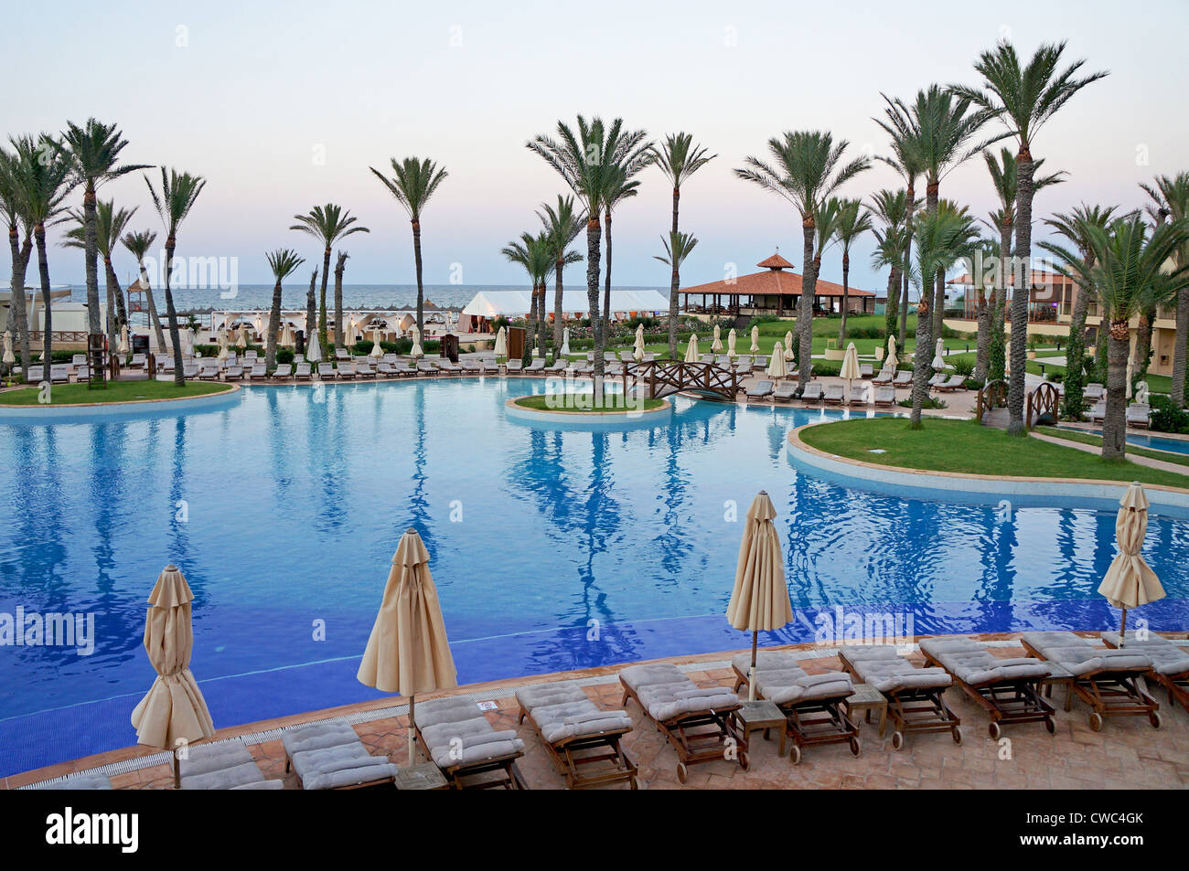 Resort swimming pool in a tropical place with sun loungers and palm