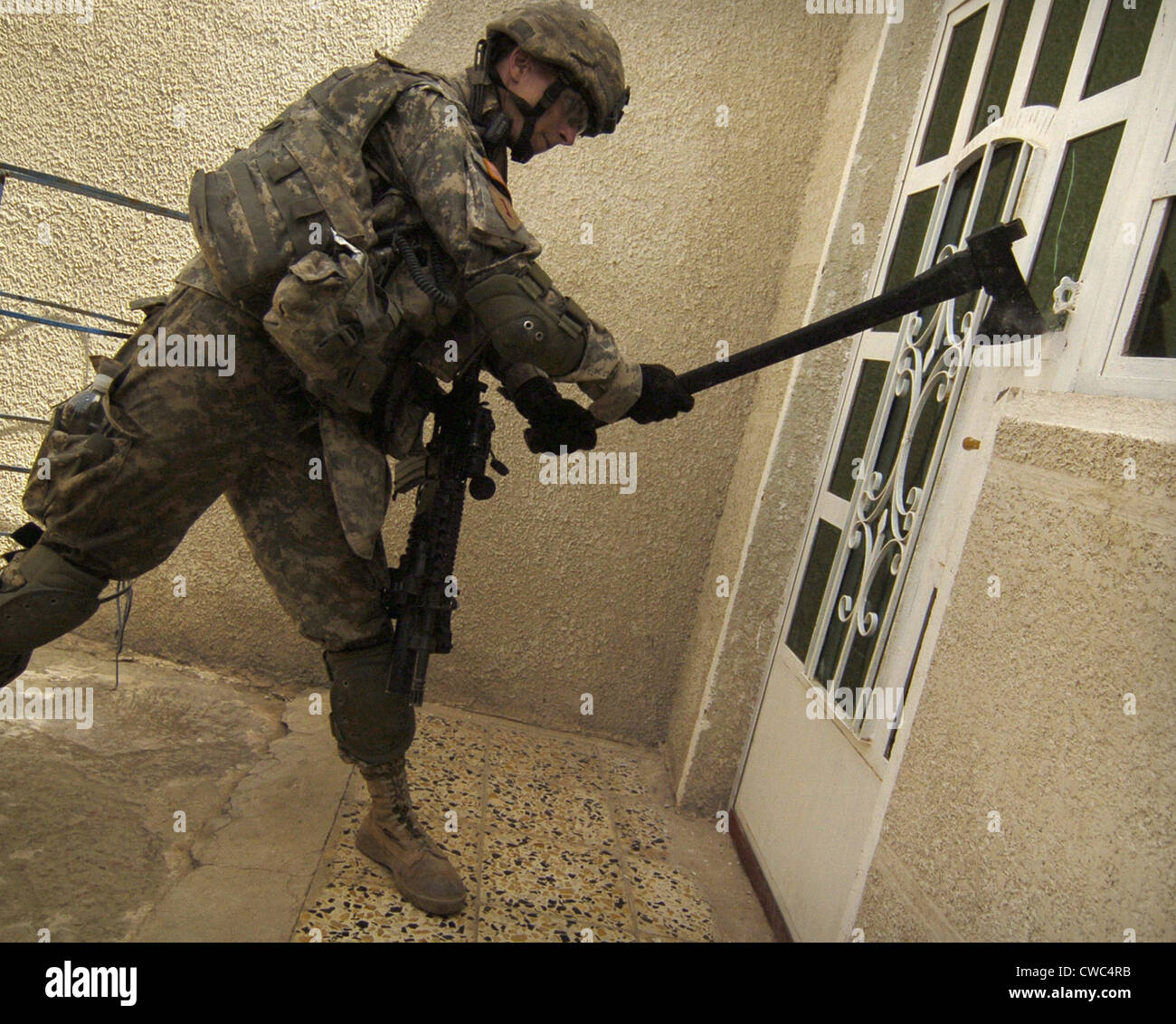 US soldier breaks down a door during a house-to-house search for illegal weapons and explosives in the Sadiyah section of Stock Photo