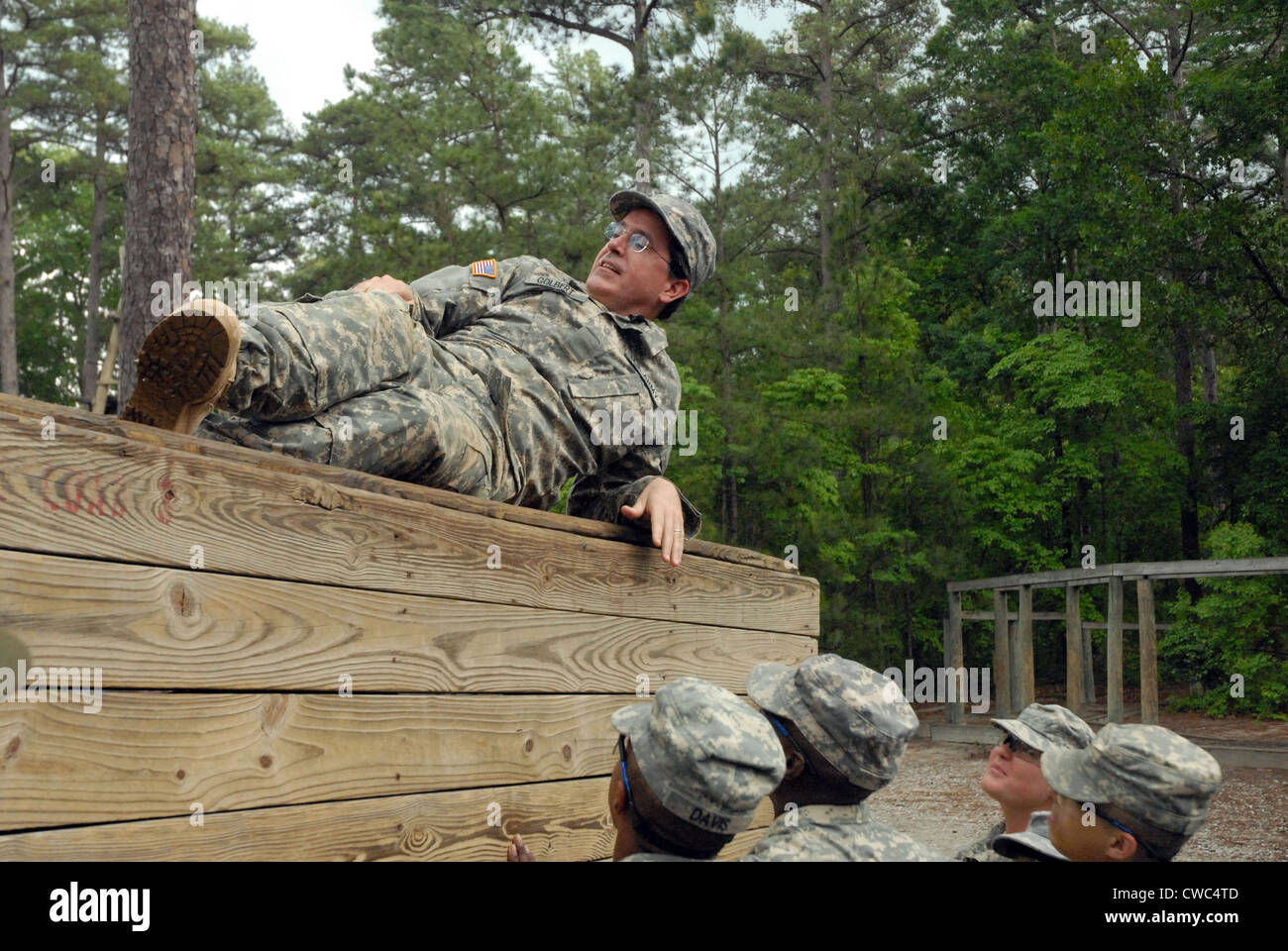 Political humorist Stephen Colbert tackles Basic Training. Army Private for a day Colbert rests atop an obstacle course wall Stock Photo