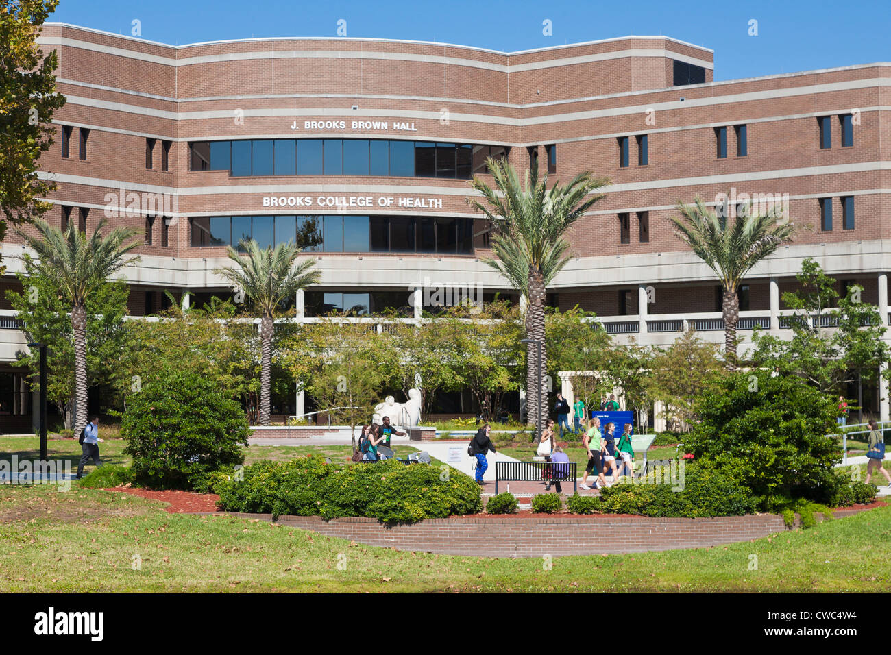 Students walk past the Brooks College of Health building at the