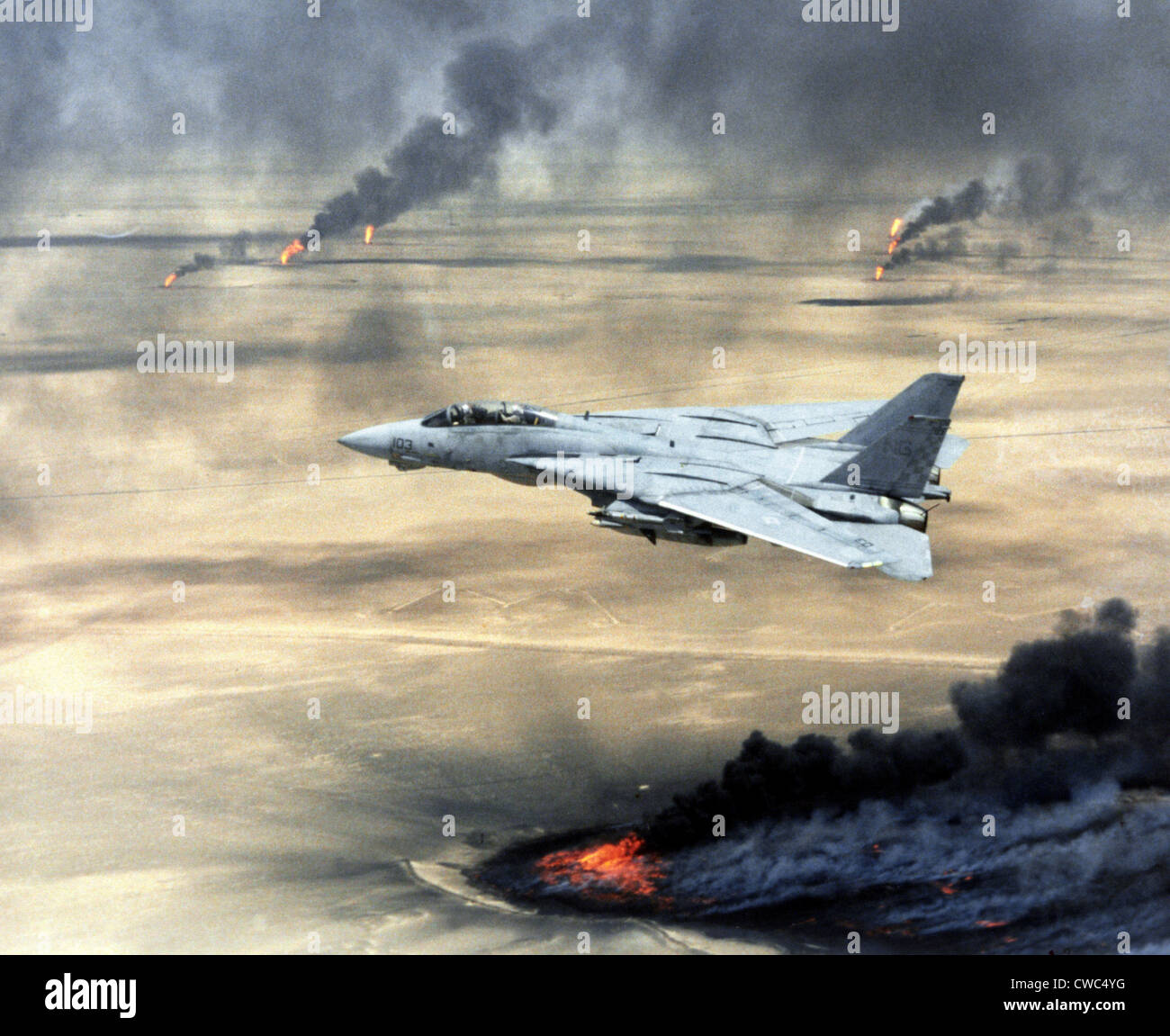 F-14 fighter in flight over burning Kuwaiti oil wells set on fire by retreating Iraqi forces during Operation Desert Storm. Stock Photo