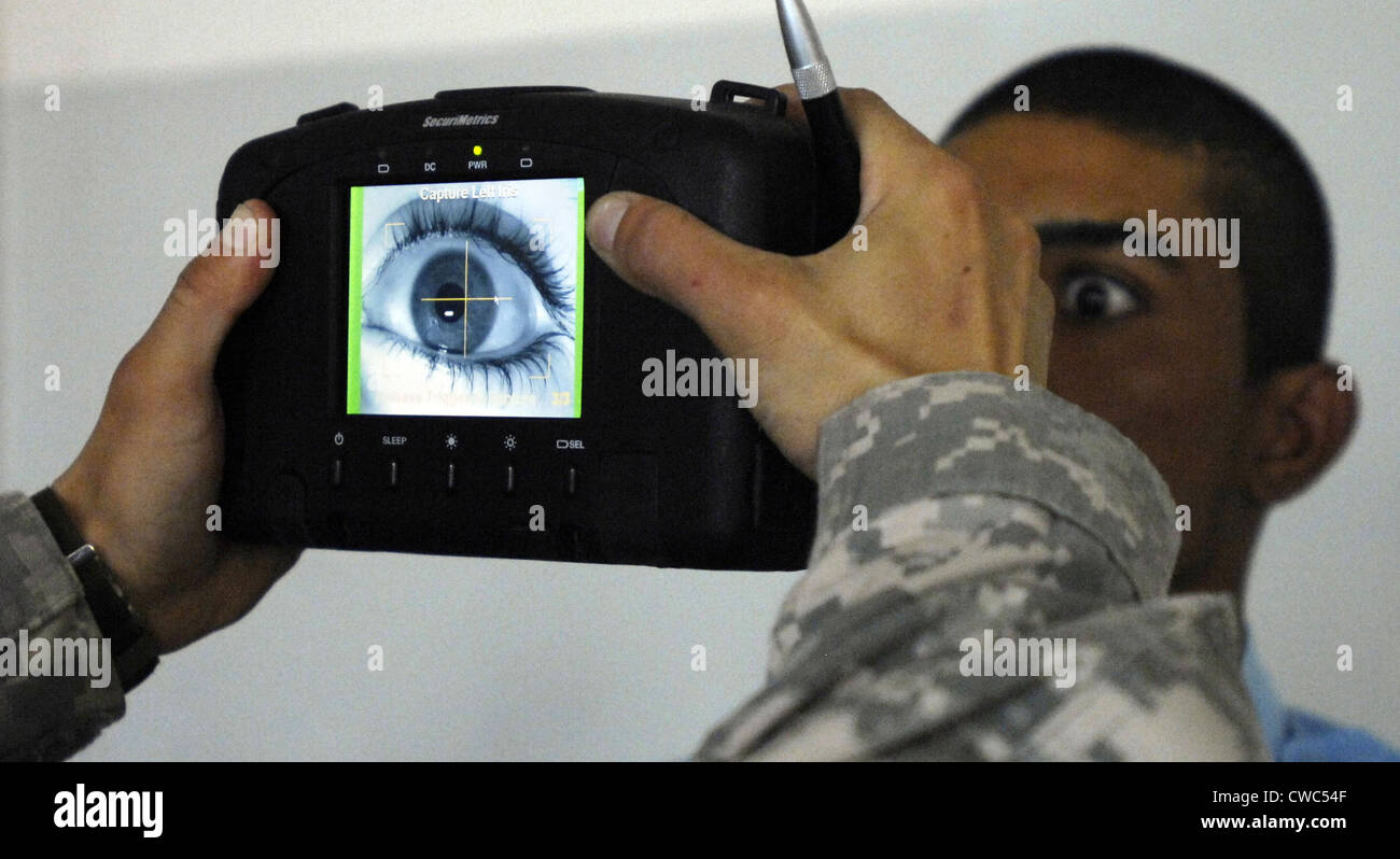 An Iraqi police recruit holds his eye open for a retinal scan administered by a US Soldier in Mahmudiyah Iraq May 30 2007. Stock Photo