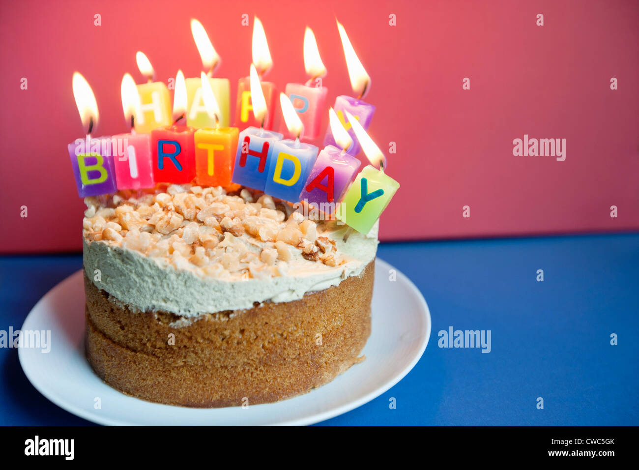 Close-up of candles burning on birthday cake over colored background