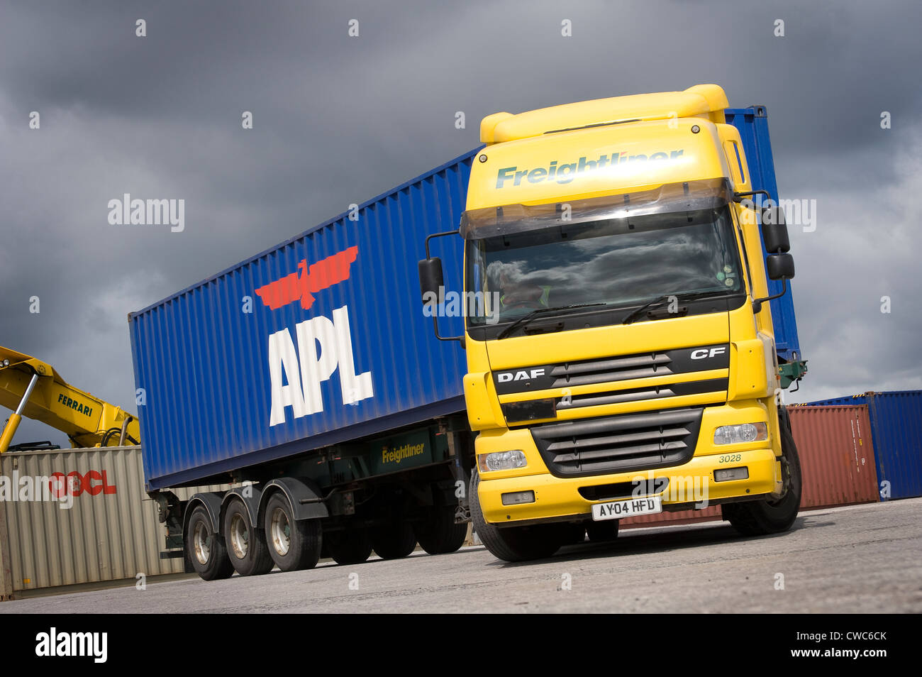 DAF lorry in freightliner livery about to leave a railway depot hauling a large shipping container. Stock Photo