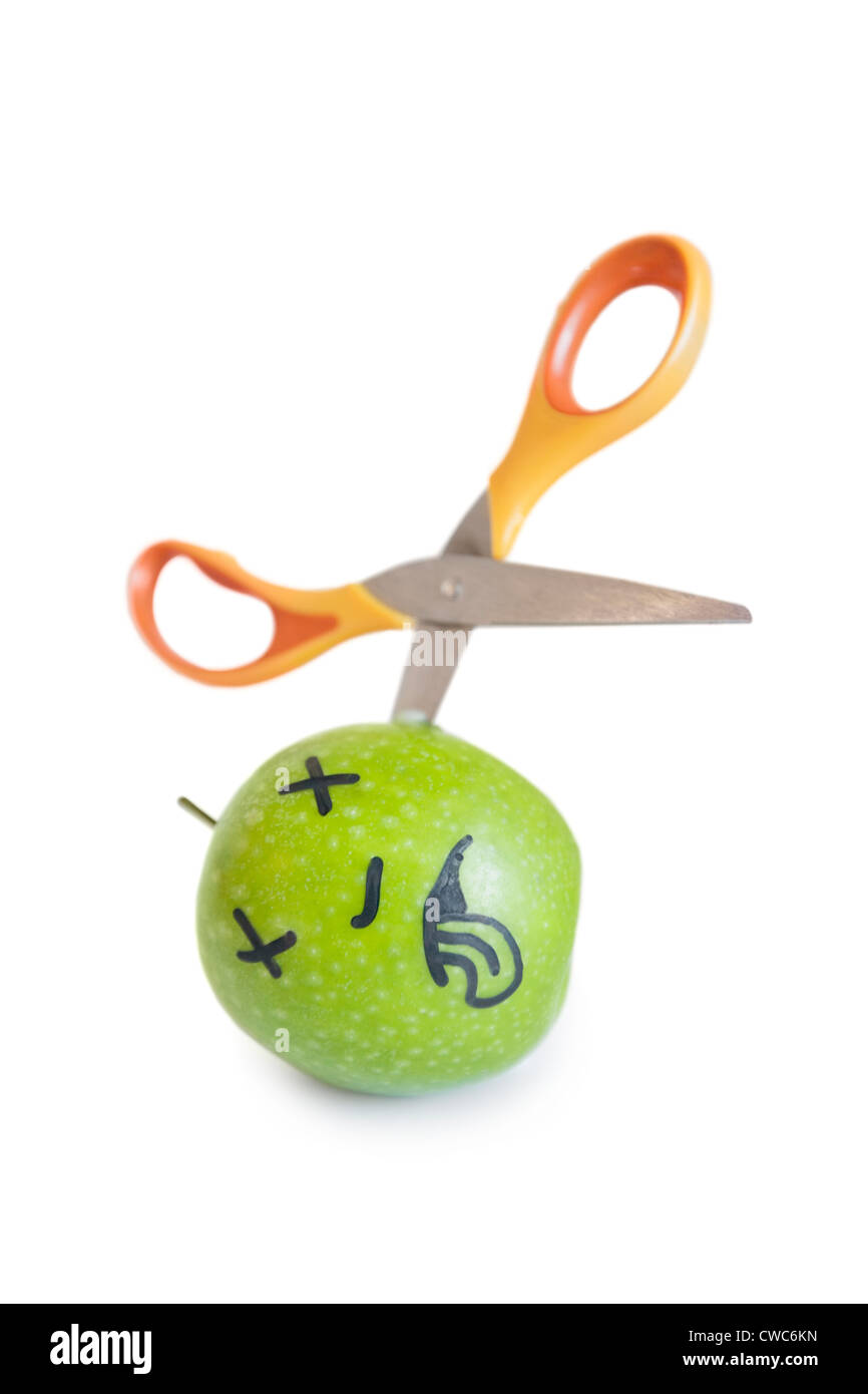 Granny smith apple murdered by scissor over white background Stock Photo
