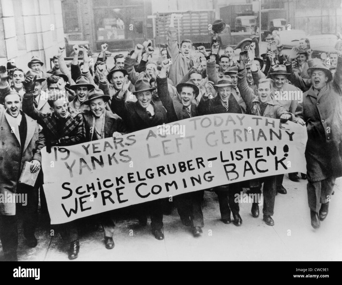 Cheering American men ready to go to war. They carry a sign reading '19