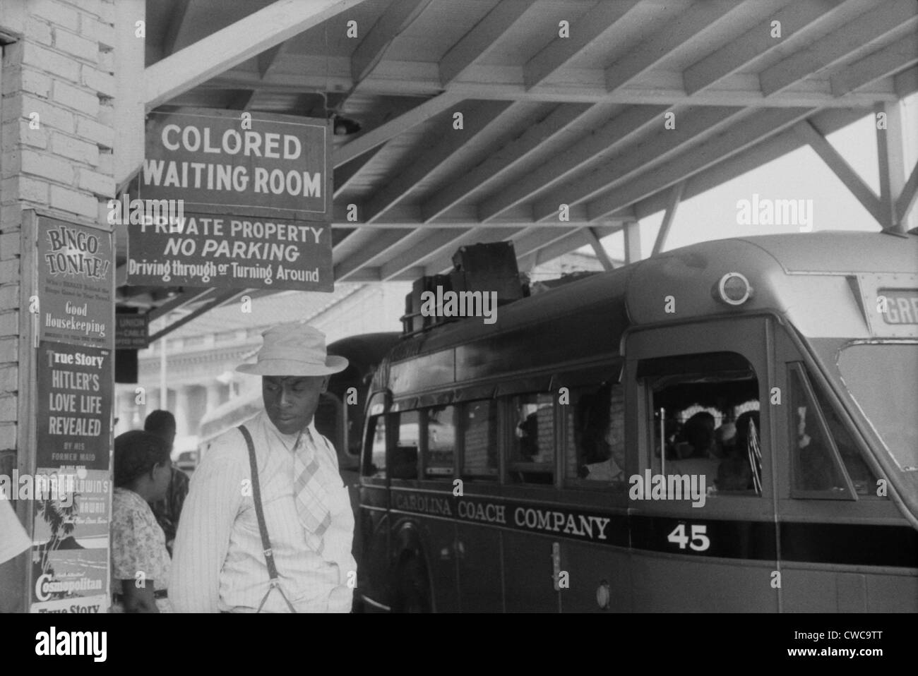 'Colored Waiting Room' sign. African Americans stand under a Jim Crow sign at the bus station in Durham, North Carolina. May Stock Photo