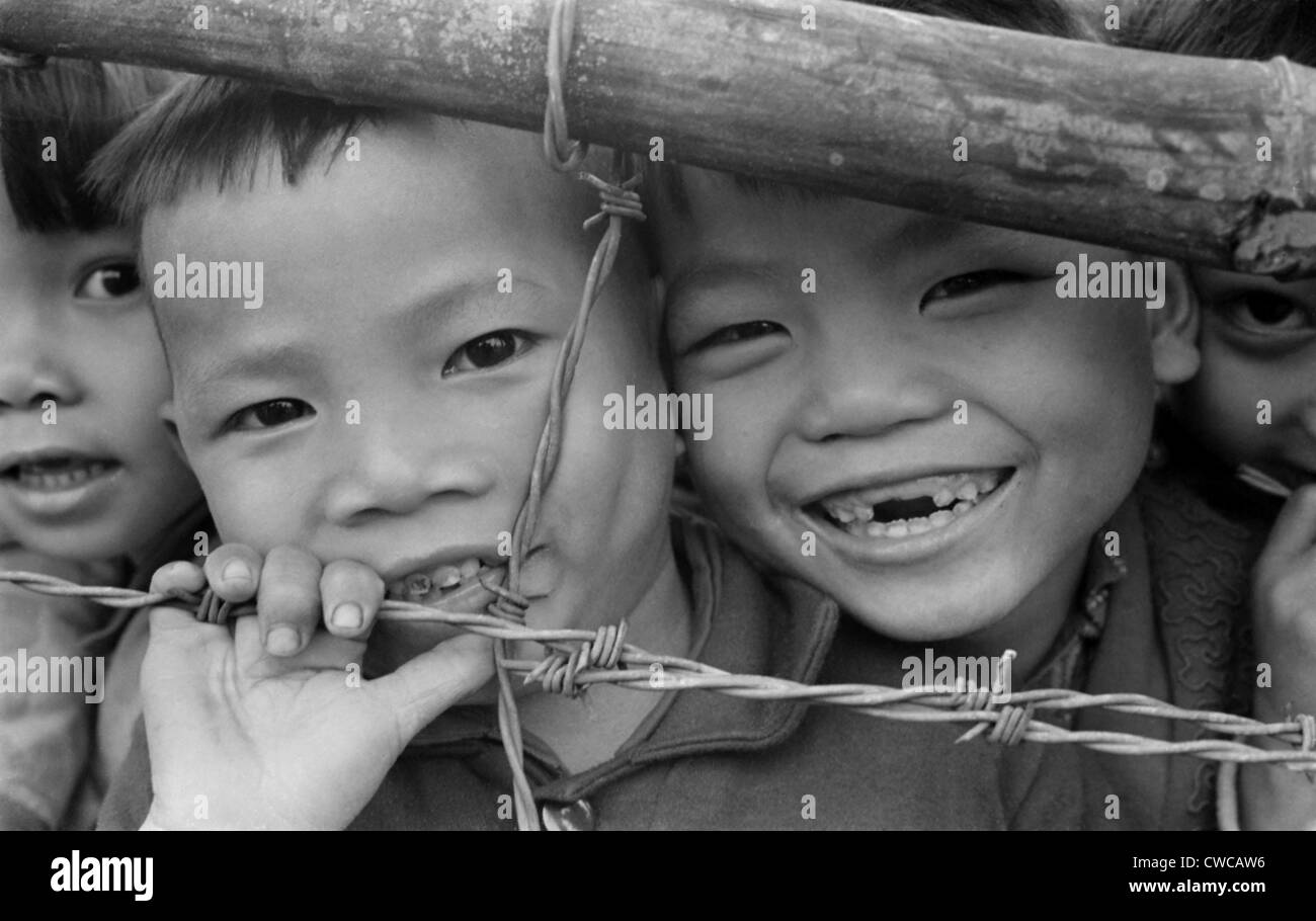 Smiling youngsters press against a barbed wire fence. There were 126 families, with over 350 children under 15 years old, in Stock Photo