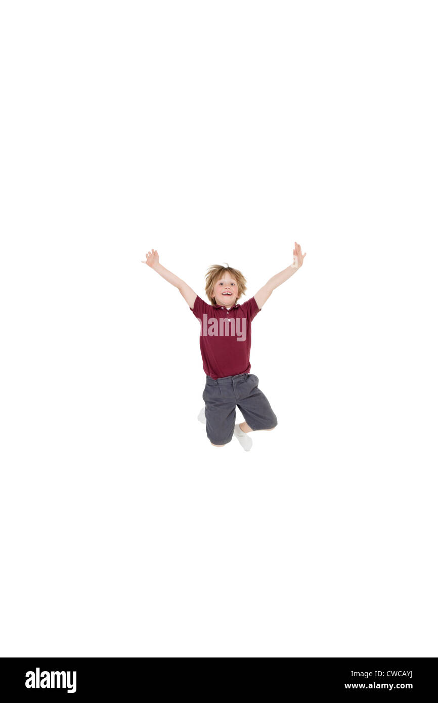 Portrait of elementary boy jumping in air with arms raised over white background Stock Photo
