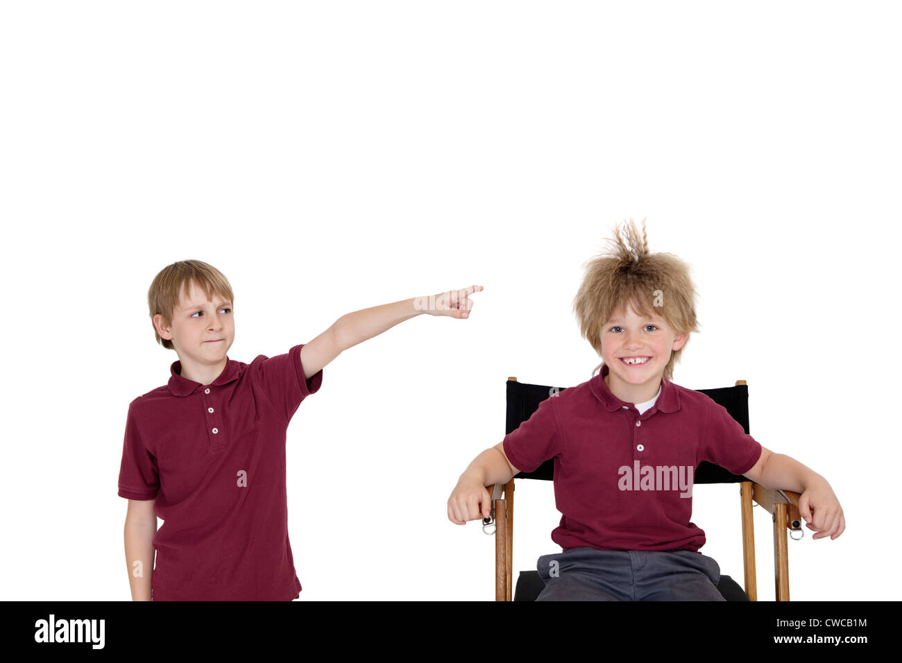 Portrait of school boy smiling while friend pointing at him over white background Stock Photo