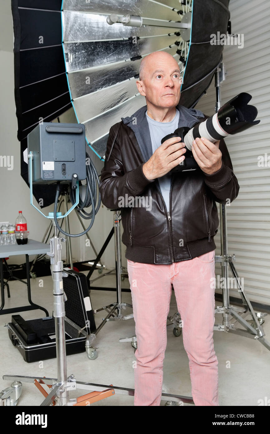 Front view of senior man with camera in photographer's studio Stock Photo
