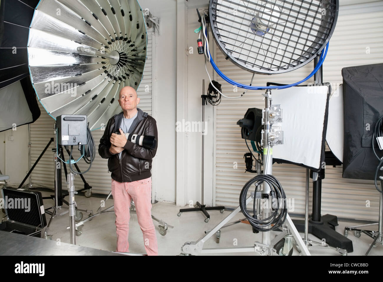 Senior photographer with camera and light reflectors in studio Stock Photo
