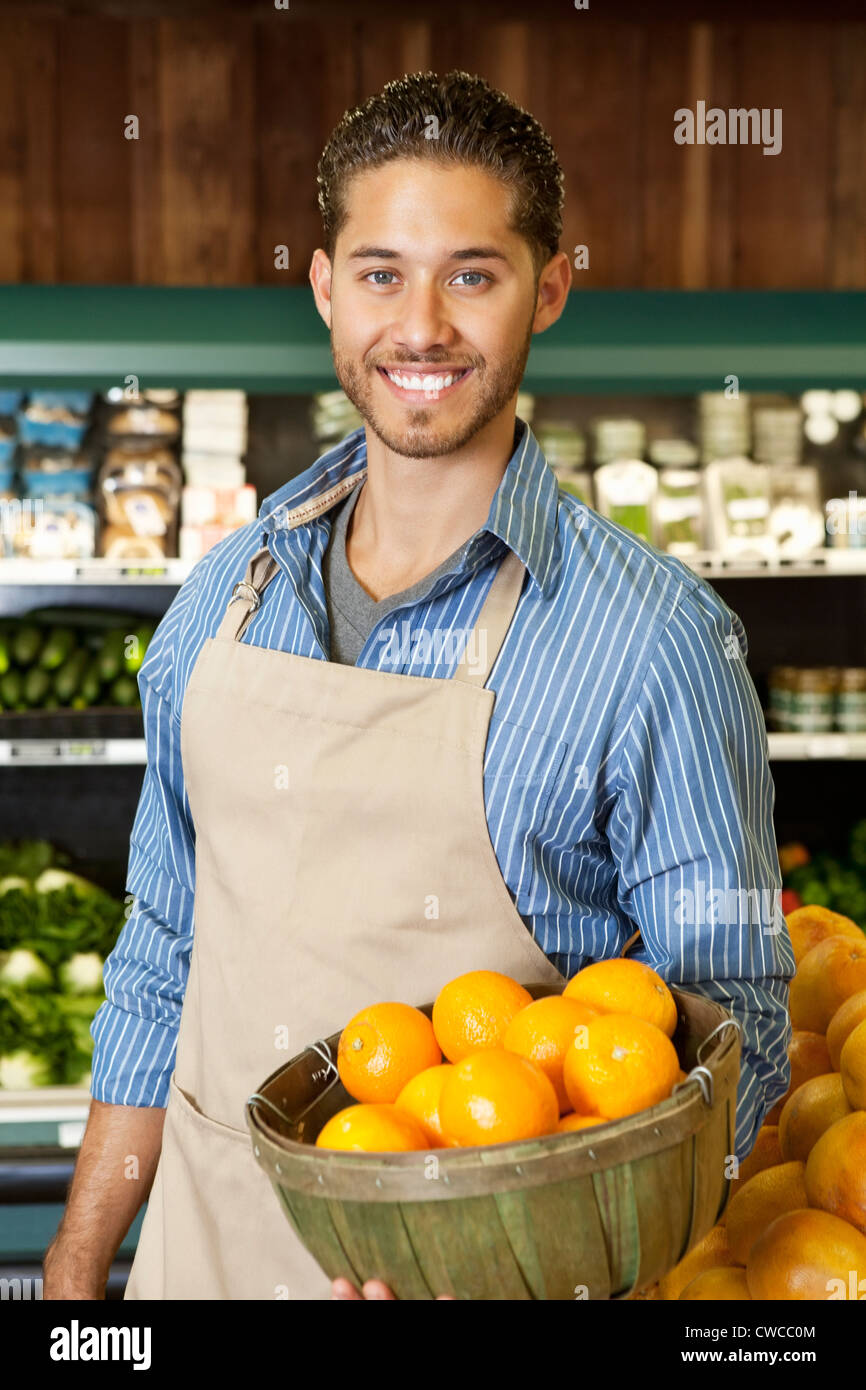 Portrait of a happy salesperson with basket full of oranges in market Stock Photo
