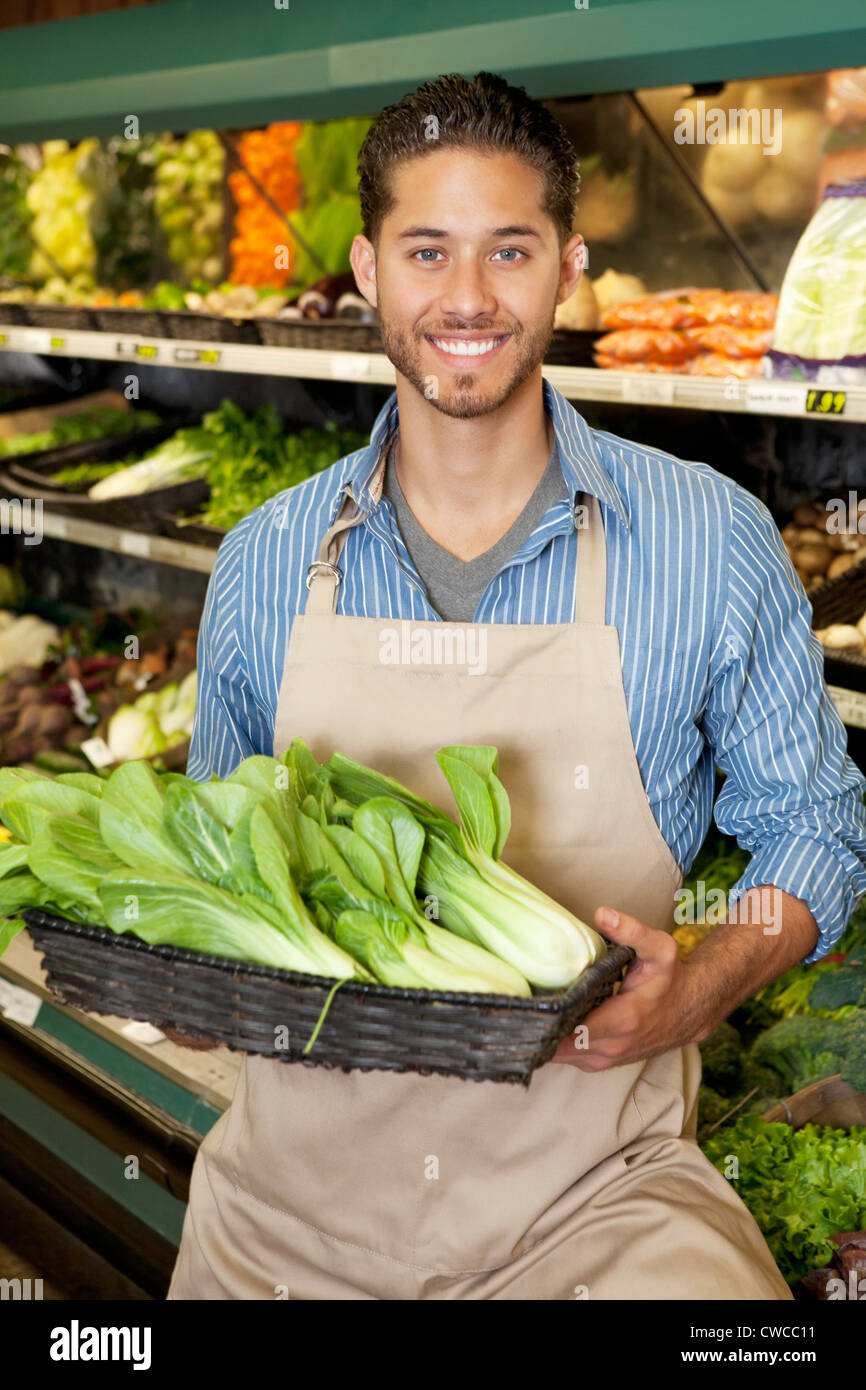 Portrait of a happy young salesperson with bok choy in market Stock Photo