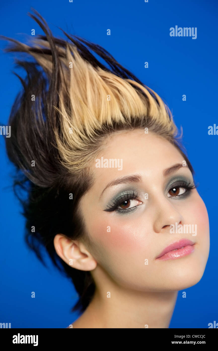 Close-up portrait of beautiful young woman with spiked hair over blue background Stock Photo
