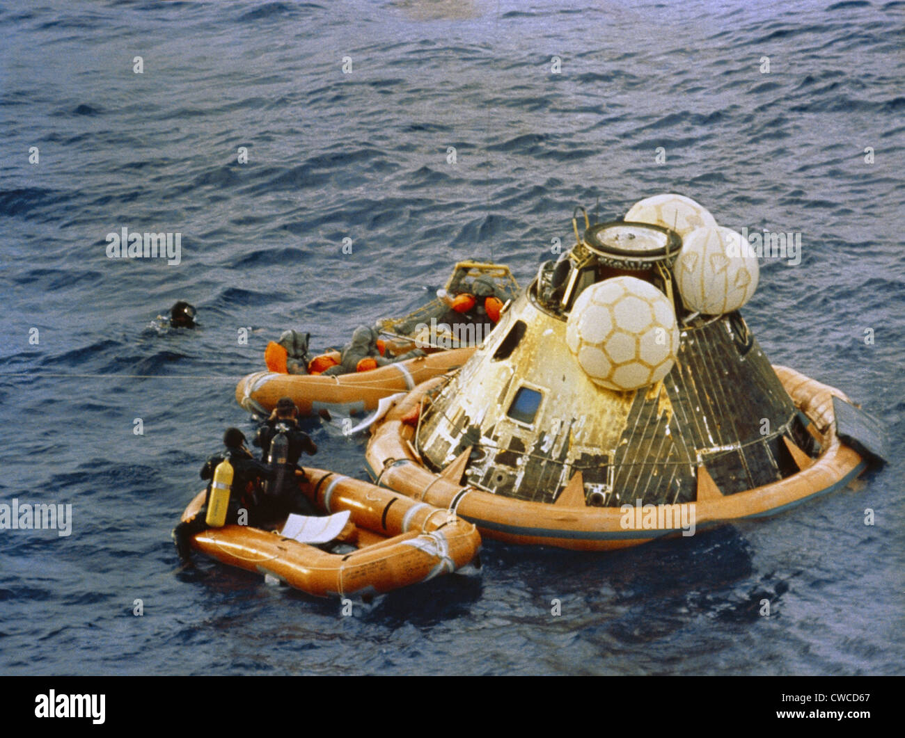 Apollo 11 Recovery. Behind the floating Command Module the astronauts are dressed in Biological Isolation Garments for their Stock Photo