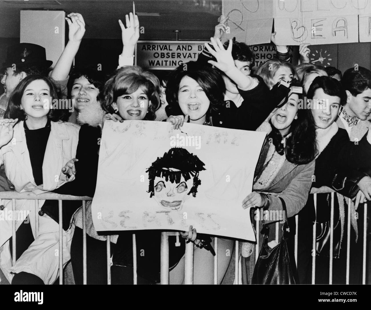 Screaming teenagers girls wave a crude sign as they welcome 'The Beatles' at New York's Kennedy Airport. Feb. 7, 1964. Stock Photo